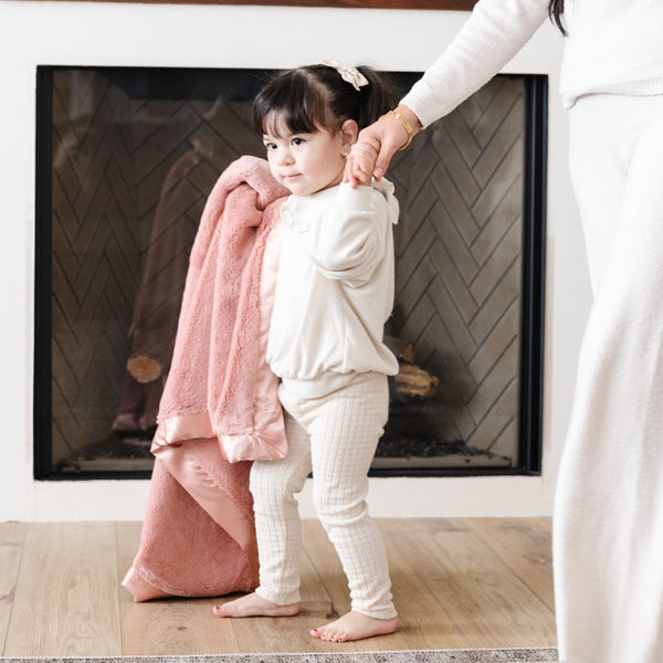 Little girl holding her cozy pink blanket.