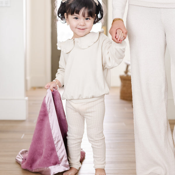 Little girl holding a cozy purple receiving blanket.