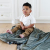 Little boy sitting on a soft and cozy green receiving blanket. 