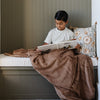 A little boy reads with a Toddler Hazelnut Colored Lush Luxury Saranoni Blanket. The soft blanket is a baby blanket or toddler blanket.