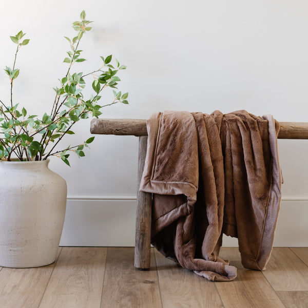 A Luxury Receiving Hazelnut Colored Lush Saranoni Blanket draped over a wooden bench. The soft blanket is a small blanket and a baby blanket or toddler blanket.