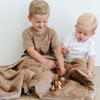 Two brothers sit under a Toddler Hazelnut Colored Lush Luxury Saranoni Blanket. The soft blanket is a baby blanket or toddler blanket.