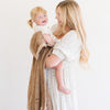 A mother holds her daughter and a Toddler Hazelnut Colored Lush Luxury Saranoni Blanket. The soft blanket is a baby blanket or toddler blanket.