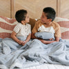 Two little boys who are brothers sit under a Luxury Toddler Gray Colored Lush Saranoni Blanket. The soft blanket is a toddler blanket or baby blanket.