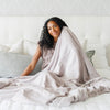 A woman holds a Luxury Extra Large Oversized Throw Feather (light gray) Colored Lush Saranoni Blanket. The soft blanket is an extra large throw blanket and has a soft faux fur feeling.