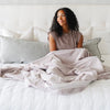 A woman holds a Luxury Extra Large Oversized Throw Feather (light gray) Colored Lush Saranoni Blanket. The soft blanket is an extra large throw blanket and has a soft faux fur feeling.