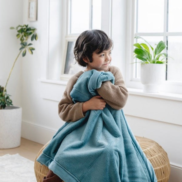 A little boy holds a Toddler Mineral Blue Colored Lush Luxury Saranoni Blanket. The soft blanket is a small blanket and a baby blanket or toddler blanket.