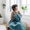 A little boy holds a Toddler Mineral Blue Colored Lush Luxury Saranoni Blanket. The soft blanket is a small blanket and a baby blanket or toddler blanket.