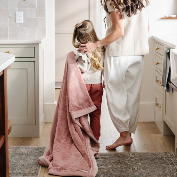 A little girl carries a Luxury Toddler Ballet Slipper (light pink) Colored Lush Saranoni Blanket. The soft blanket is a toddler blanket or baby blanket.