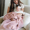 A mother holds her baby girl in a Luxury Receiving Ballet Slipper (light pink) Colored Lush Saranoni Blanket. The soft blanket is a small blanket and a baby blanket or toddler blanket.