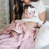 A mother holds her baby girl in a Luxury Receiving Ballet Slipper (light pink) Colored Lush Saranoni Blanket. The soft blanket is a small blanket and a baby blanket or toddler blanket.