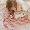 A mother holds her baby girl in a Luxury Receiving Ballet Slipper (light pink) Colored Lush Saranoni Blanket. The soft blanket is a small blanket and a baby blanket or toddler blanket.