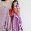 A little girl holds a Luxury Toddler Fairy Wings (light pink purple) Colored Lush Saranoni Blanket. The soft blanket is a toddler blanket or baby blanket.