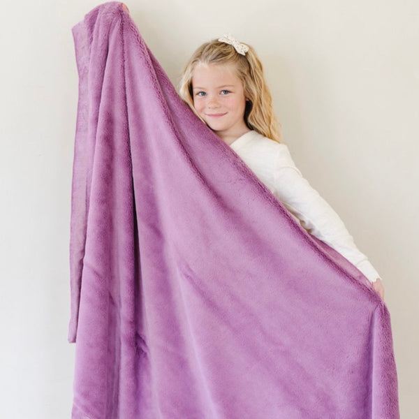 A little girl holds a Luxury Toddler Fairy Wings (light pink purple) Colored Lush Saranoni Blanket. The soft blanket is a toddler blanket or baby blanket.