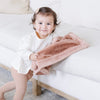 A little girl holds a mini Rosy (dusty peach) Colored Lush Saranoni Blanket. The soft blanket is a small blanket and a baby blanket or toddler blanket.