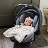 A baby girl lays in her carseat with a Natural (off-white) Colored Lush Saranoni Blanket draped over her. The soft blanket is a small blanket and a baby blanket or toddler blanket.