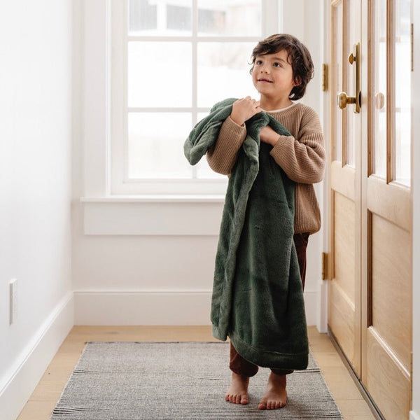 A little boy holds a Luxury Receiving Hunter Green Colored Lush Saranoni Blanket. The soft blanket is a small blanket and a baby blanket or toddler blanket.