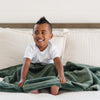 A little boy holds a Toddler Hunter Green Colored Lush Luxury Saranoni Blanket. The soft blanket is small blanket and a baby blanket or toddler blanket.