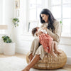 A little girl lays on her mother's lap under a Clay Colored Lush Saranoni Blanket. The soft blanket is a small blanket and a baby blanket or toddler blanket.