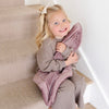 A little girl holds a Bloom (dusty purple) Colored Lush Saranoni Blanket. The soft blanket is small blanket and a baby blanket or toddler blanket.