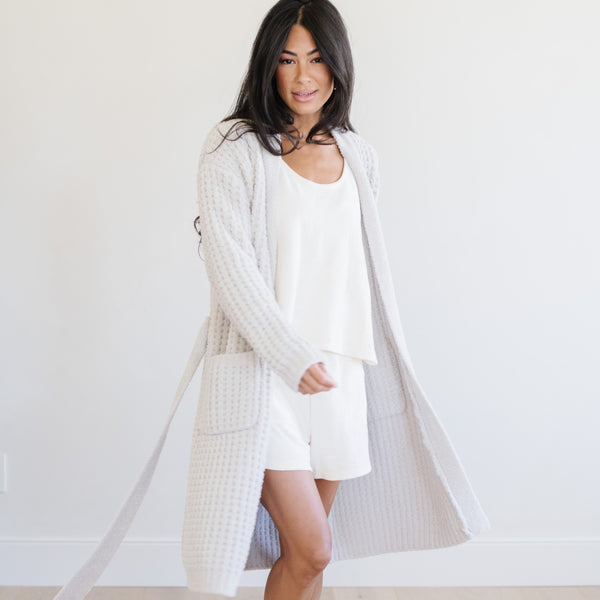 Woman standing at home, wearing a soft, gray waffle knit robe.