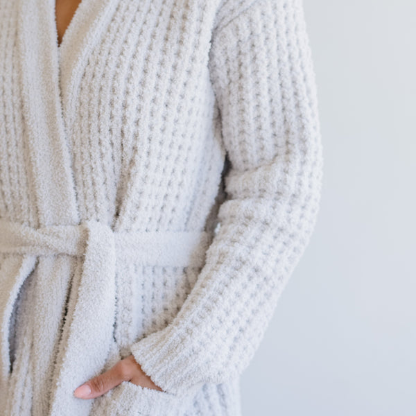 Detailed view of the intricate waffle weave pattern on a light gray waffle knit robe. 