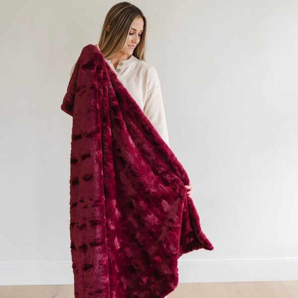 Woman showcasing the thickness of the Patterned Faux Fur blanket and the luxury feel. 