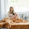 Kids and mom snuggling in a Saranoni Extra Large Throw Blanket, enjoying its fluffy softness.