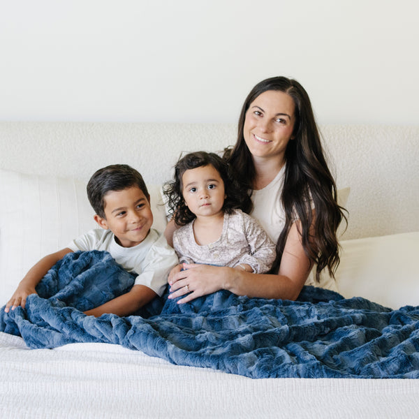 Mother and children snuggled up in a Saranoni patterned faux fur XL throw blanket.