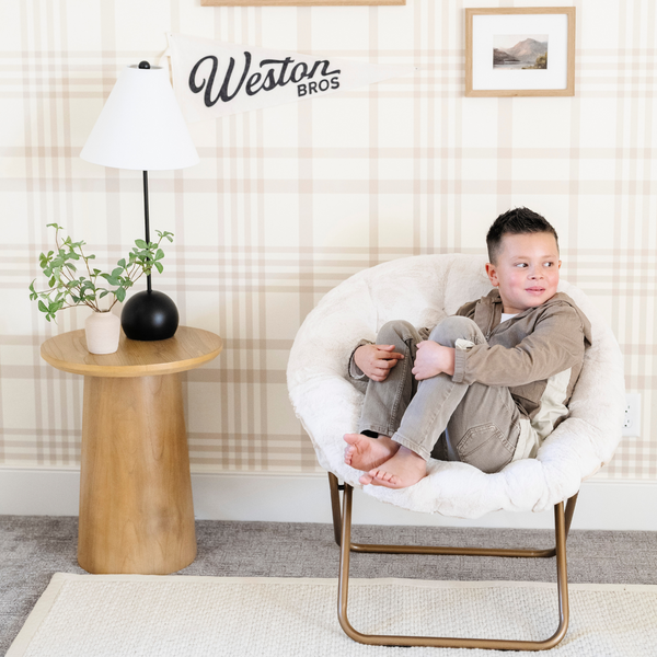 A little boy lounging in a cozy cream Saranoni faux fur saucer chair, featuring a soft, removable faux fur cover made from the same luxurious fabric as Saranoni’s blankets. This stylish and foldable saucer chair offers a safe, comfortable space for kids to relax, read, or play. Perfect for adding warmth and texture to any room, it’s a must-have for creating a kid-friendly lounging spot.