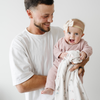 Dad holding baby girl wearing a light pink bamboni lite outfit. 