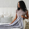 Girl with dark curly hair arranging a luxurious xl chenille fringe blanket on a bed - Saranoni