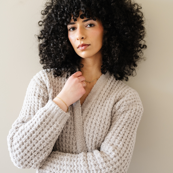 Woman wearing a tan oatmeal colored robe that is waffle knit. 