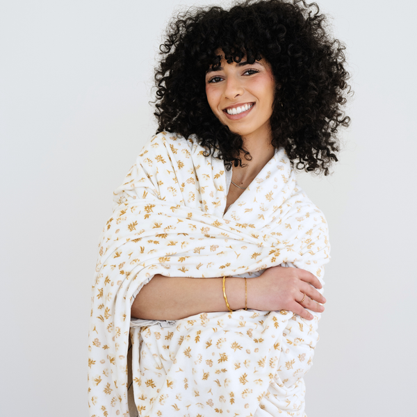 Woman wrapped in a neutral florals minky stretch blanket. 