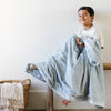 A little boy holds a Luxury Toddler Chambray (cloud-like light blue) Colored Lush Saranoni Blanket draped over his lap. The soft blanket is a toddler blanket.