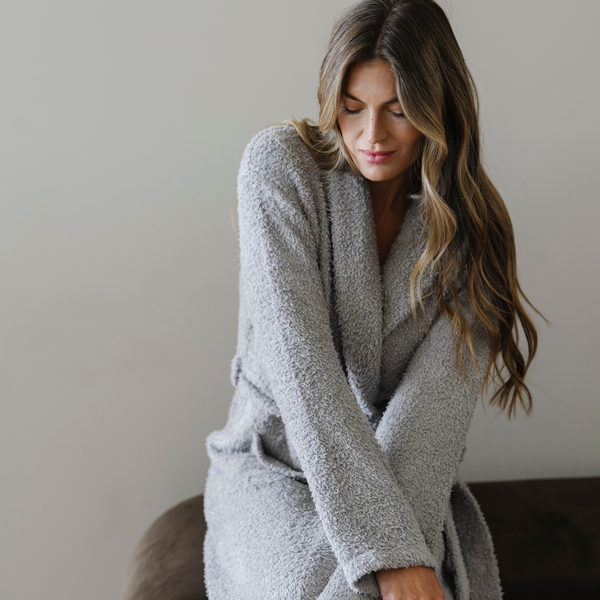 Woman snuggled wearing a gray bamboni cozy luxury robe. 