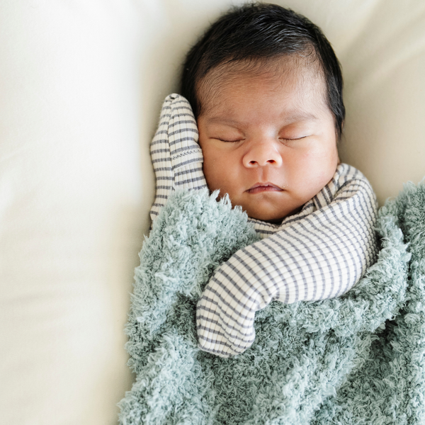 Baby boy snuggled with very soft Surf Ribbed Bamboni® Mini Blanket.