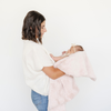 Mom holding baby girl wrapped in a blush pink ream faux fur receiving baby blanket. 
