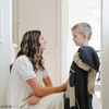 A little boy stands by his mom while holding a black and light gray double-layer Bamboni® blanket with a Batman™ icon on it. The soft blanket is a luxury blanket and a kids blanket as well as a Saranoni blanket. This kids blanket is perfect for littles. 