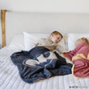 A little boy lays in a black and light gray double-layer Bamboni® blanket with a Batman™ icon on it. The soft blanket is a luxury blanket and a receiving blanket as well as a Saranoni blanket. This kids blanket is perfect for littles. 