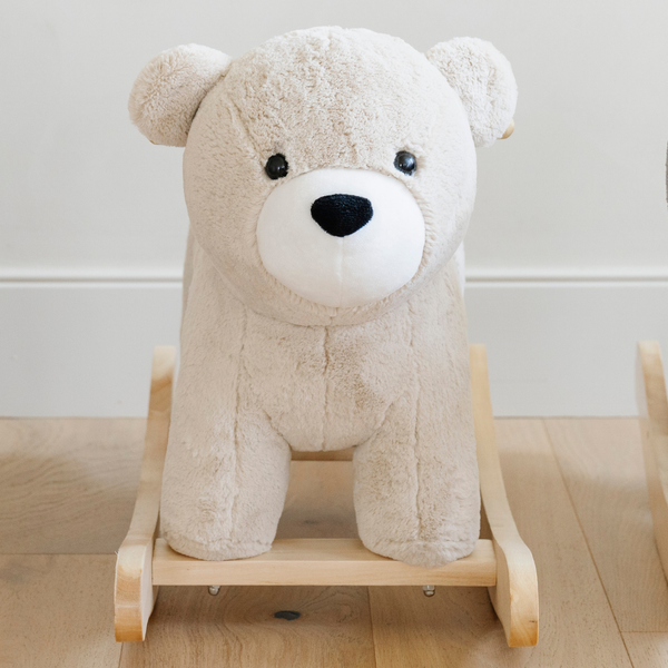 A close-up view of a soft, beige plush bear rocker, featuring a round face with a friendly expression and a contrasting white snout. The plush texture invites touch, making it an appealing addition to children's playrooms. Perfect for parents looking for high-quality, cuddly rocking toys that provide both comfort and fun for their little ones.