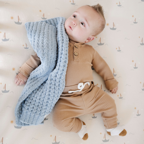 A baby boy with a buttery-soft Saranoni blanket, featuring a breathable, plush waffle texture in a soothing blue hue. This luxury mini blanket is the best baby blanket as a newborn blanket and infant blanket—perfect as a cozy blanket for snuggles or a must-have infant blanket. Designed for softness and comfort, this plush baby blanket makes an ideal baby boy gift or gift for new moms. Enjoy this luxury blanket!