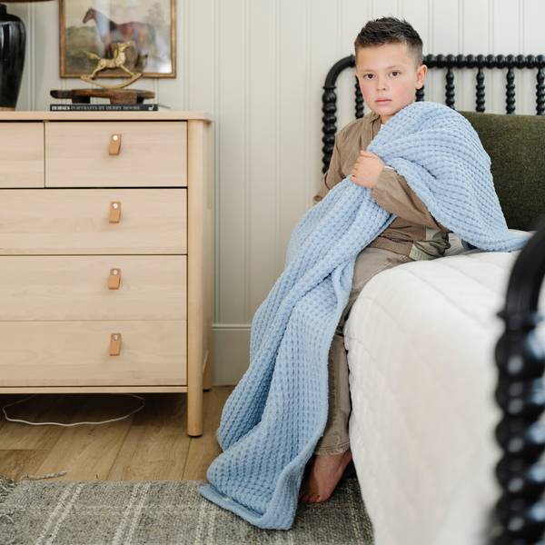 A little boy holds a buttery-soft Saranoni blanket, featuring a breathable, plush waffle texture in a soothing blue hue. This luxury toddler blanket is the best kids blanket as a baby blanket or toddler blanket—perfect as a cozy blanket for snuggles or a must-have infant blanket. Designed for softness and comfort, this plush toddler blanket makes an ideal toddler gift. Enjoy this luxury blanket!