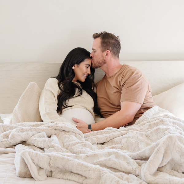 A husband and wife sit with a light tan luxurious patterned faux fur extra large throw blanket that is a Saranoni blanket. This ultra-soft, cozy blanket adds a touch of elegance and warmth to any space, perfect as a soft oversized blanket or fluffy blanket for lounging. Ideal for those seeking a high-quality artificial fur blanket or luxury blanket, this versatile and stylish soft blanket enhances both comfort and decor. Shop the best blankets and throws for ultimate relaxation and cozy vibes.