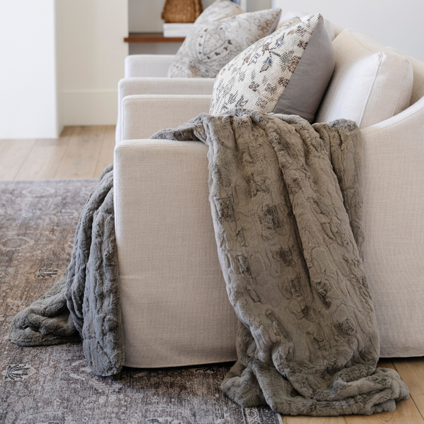 A cashmere colored luxurious patterned faux fur extra large throw blanket that is a Saranoni blanket is draped over a couch. This ultra-soft, cozy blanket adds a touch of elegance and warmth to any space, perfect as a soft oversized blanket or fluffy blanket for lounging. Ideal for those seeking a high-quality artificial fur blanket or luxury blanket, this versatile and stylish soft blanket enhances both comfort and decor. Shop the best blankets and throws for ultimate relaxation and cozy vibes.