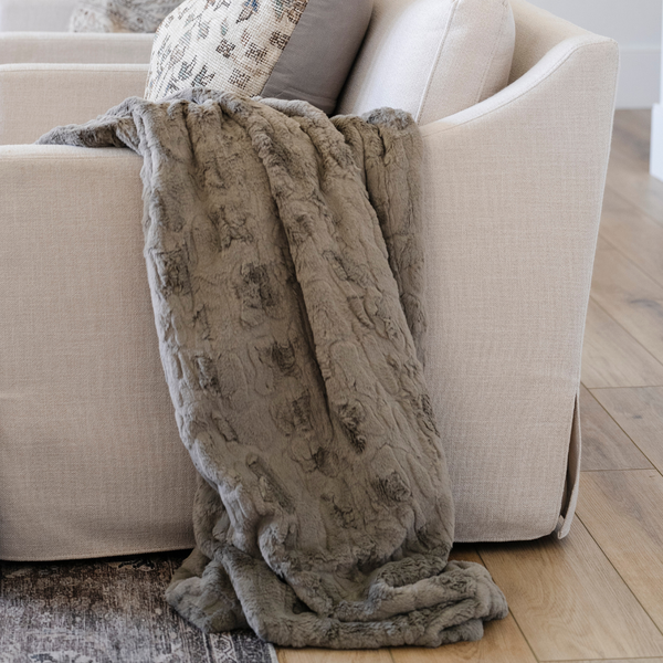 A cashmere colored luxurious patterned faux fur throw blanket that is a Saranoni blanket draped on a couch. This ultra-soft, plush throw blanket adds a touch of elegance and warmth to any space, perfect as a soft throw blanket or fluffy blanket for lounging. Ideal for those seeking a high-quality artificial fur blanket or luxury blanket, this versatile and stylish soft blanket enhances both comfort and decor. Shop the best blankets and throws for ultimate relaxation and cozy vibes.