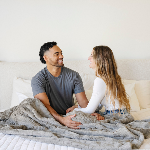 A husband and wife sit by a cashmere colored luxurious patterned faux fur extra large throw blanket that is a Saranoni blanket. This ultra-soft, cozy blanket adds a touch of elegance and warmth to any space, perfect as a soft oversized blanket or fluffy blanket for lounging. Ideal for those seeking a high-quality artificial fur blanket or luxury blanket, this versatile and stylish soft blanket enhances both comfort and decor. Shop the best blankets and throws for ultimate relaxation and cozy vibes.