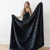 A woman holds a charcoal luxurious patterned faux fur throw blanket that is a Saranoni blanket. This ultra-soft, plush throw blanket adds a touch of elegance and warmth to any space, perfect as a soft throw blanket or fluffy blanket for lounging. Ideal for those seeking a high-quality artificial fur blanket or luxury blanket, this versatile and stylish soft blanket enhances both comfort and decor. Shop the best blankets and throws for ultimate relaxation and cozy vibes.