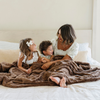 A woman and her son and daughter sit with a brown luxurious patterned faux fur throw blanket that is a Saranoni blanket. This ultra-soft, plush throw blanket adds a touch of elegance and warmth to any space, perfect as a soft throw blanket or fluffy blanket for lounging. Ideal for those seeking a high-quality artificial fur blanket or luxury blanket, this versatile and stylish soft blanket enhances both comfort and decor. Shop the best blankets and throws for ultimate relaxation and cozy vibes.