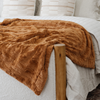 A copper colored luxurious patterned faux fur extra large throw blanket that is a Saranoni blanket is on a bed. This ultra-soft, cozy blanket adds a touch of elegance and warmth to any space, perfect as a soft oversized blanket or fluffy blanket for lounging. Ideal for those seeking a high-quality artificial fur blanket or luxury blanket, this versatile and stylish soft blanket enhances both comfort and decor. Shop the best blankets and throws for ultimate relaxation and cozy vibes.